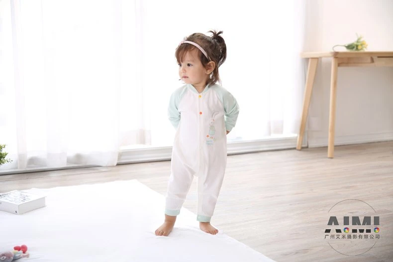 Profile of a toddler in a raglan romper standing with arms behind her back