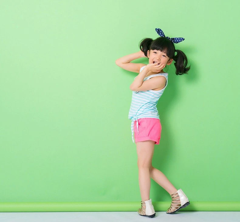 Child model in an aqua striped tie-side tank and pink shorts with a polka-dot bow