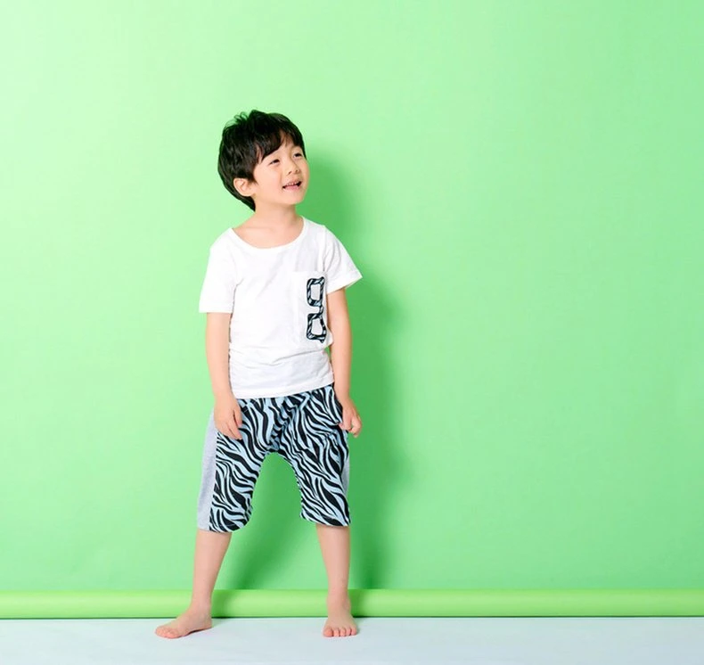 Boy model in a white tee with zebra number-8 pocket and zebra harem shorts, barefoot