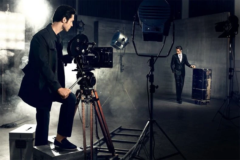 Creative double exposure of the same model as cameraman and as suited on-screen talent on a film set