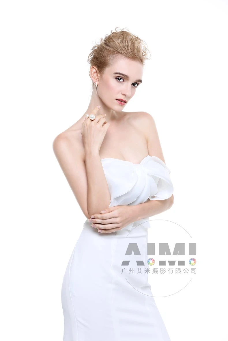 Pearl statement ring and gold linear drop earring styled against white dress drape