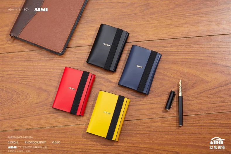 Metal card case colorways arranged with leather notebook and fountain pen - executive desk flat lay photography