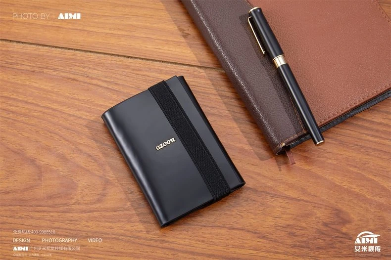 Black metal card holder with gold trim beside notebook and pen - styled product photography