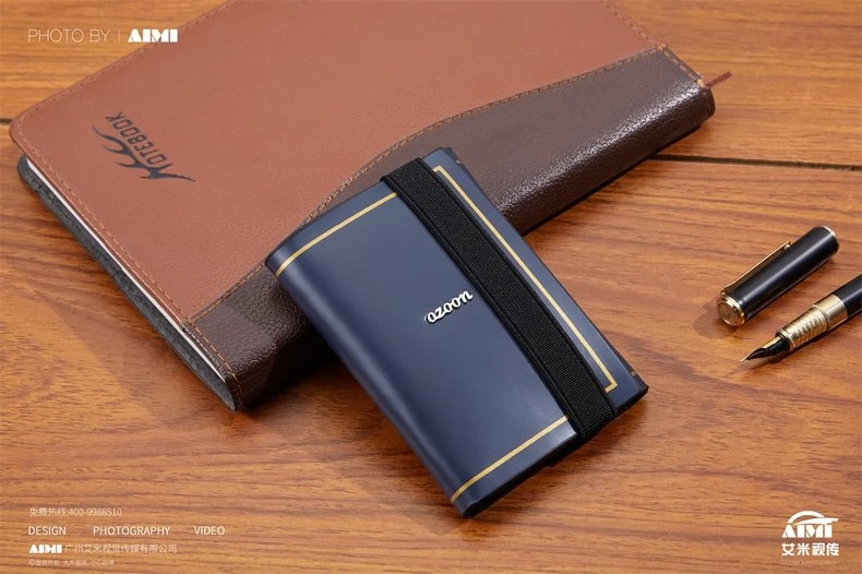 Navy card holder with elastic strap next to embossed notebook - office lifestyle product photography