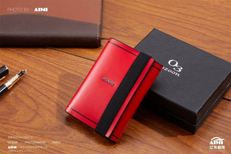 Red card case leaning on black gift box with pens - product and packaging photography