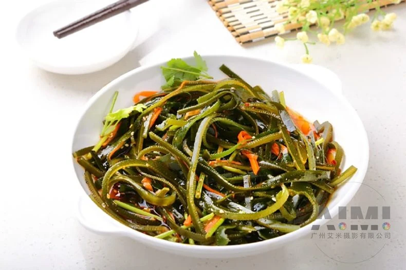 Shredded kelp salad with chili rings and sesame on a white plate
