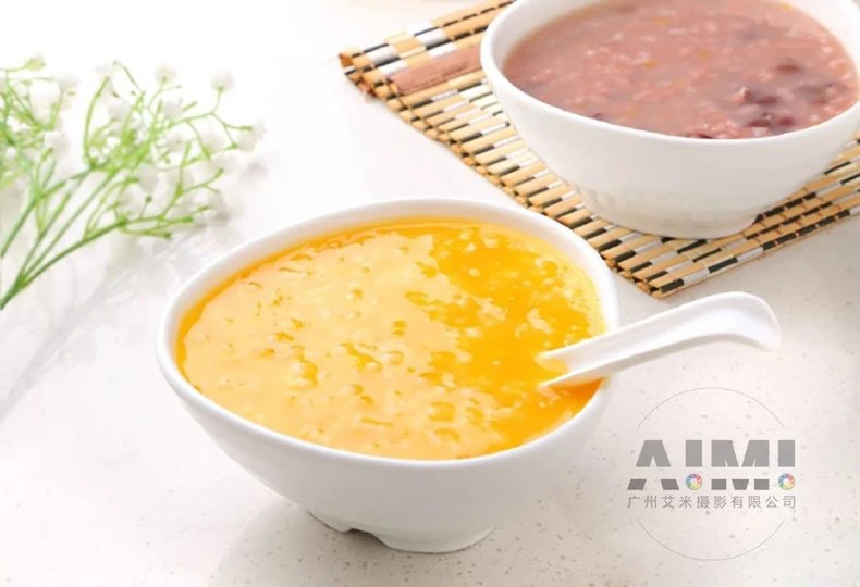 Golden pumpkin congee with red beans in a white bowl on white