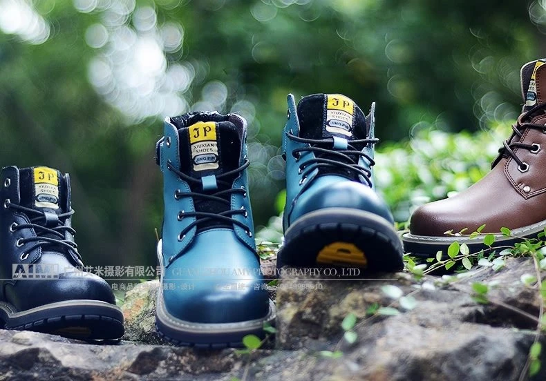 Black, teal and brown leather work boots arranged on rocks, three colorways in one outdoor frame