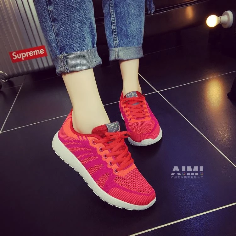 Red-orange gradient knit mesh sneakers styled with cuffed jeans, on-foot close-up