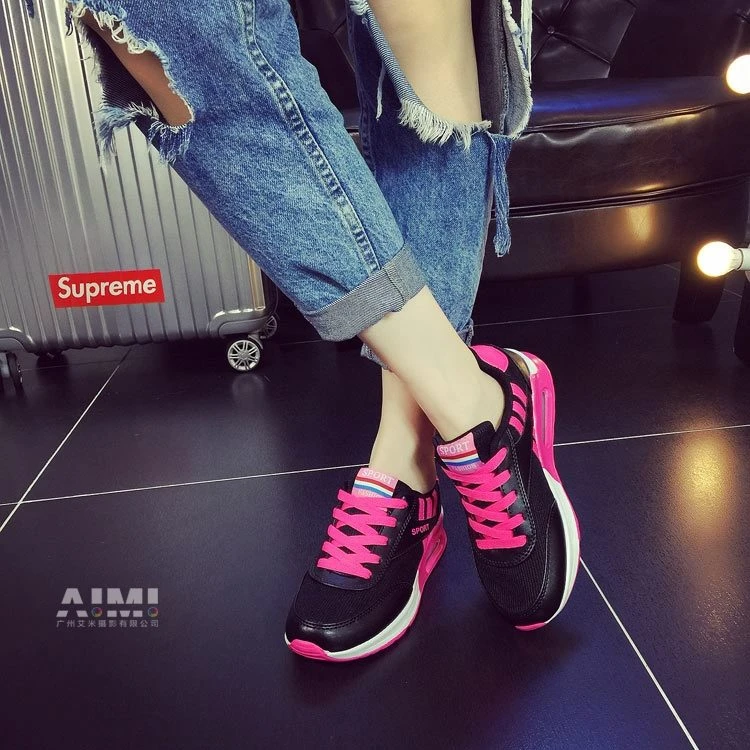 Black and hot-pink air-cushion platform sneakers with ripped denim, low on-foot three-quarter view