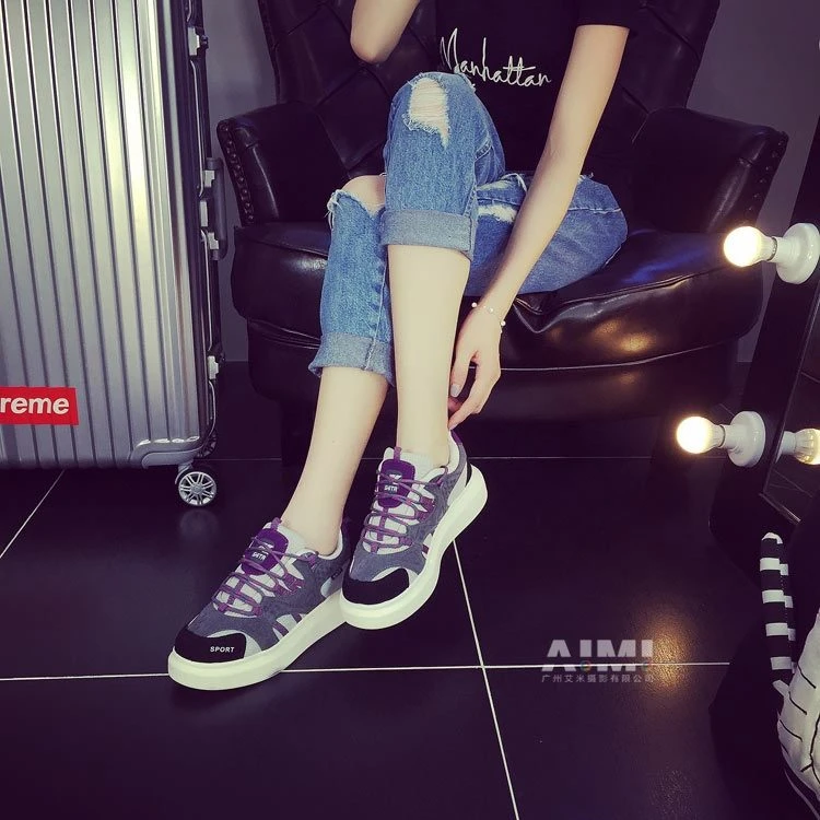 Black, gray and purple chunky platform sneakers on a seated model in the dark dressing-room set