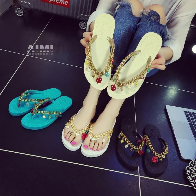 Ivory flip-flop sandals with gold chain and charm details, worn pair beside turquoise and black colorways