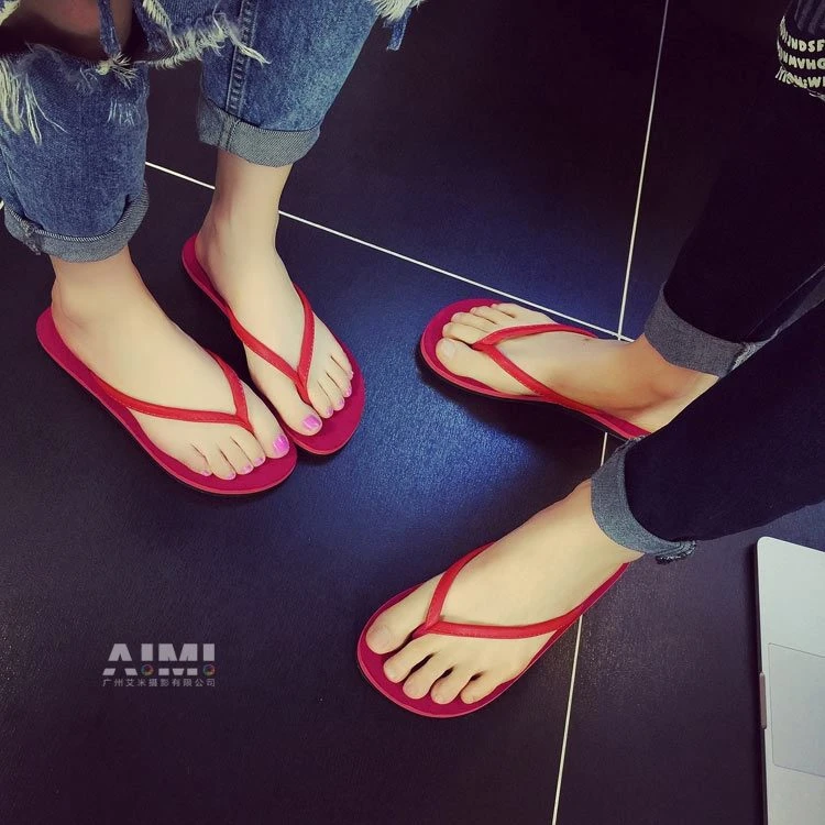 Red thong flip-flops on two pairs of feet, matching-pair top-down frame on dark tile