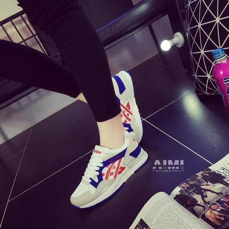 White retro runner sneakers with red and royal-blue geometric accents, heel lifted to show the tread
