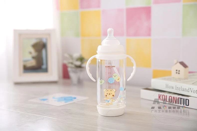 MORE CARE weighted-straw baby bottle with winking bear print and side handles, shallow depth nursery lifestyle photography