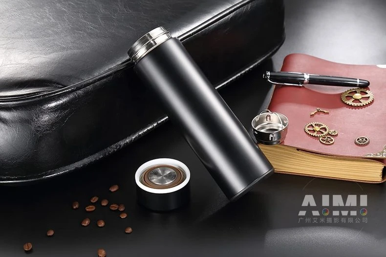 Black flask with cap and strainer beside leather book - flask parts photography
