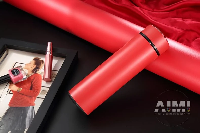 Red flask lying on glossy black with red roll backdrop - editorial bottle photography