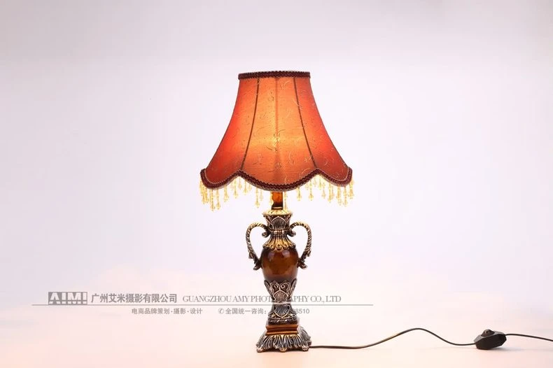 Lit rust table lamp with cord on white - bedside lamp photography