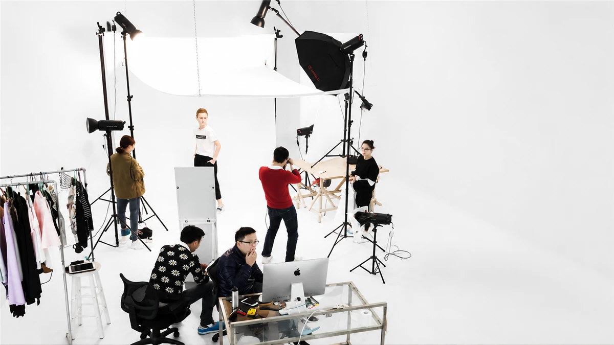 Multi-strobe lighting array on AIMI's white cyclorama — octabox key light, suspended diffusion scrim, and reflector fill